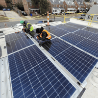 Two workers work on a solar panel.