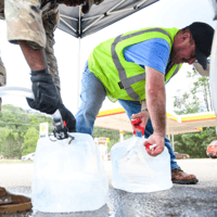 An Army National Guard member assists a resident with potable water in the aftermath of Hurricane Helene on Sept. 29 in Old Fort, N.C. (Photo: Melissa Sue Gerrits/Getty Images)